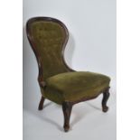 A Victorian mahogany spoon back nursing chair raised on cabriole legs with hoof feet having green