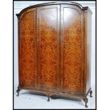 A Queen Anne revival triple wardrobe compactum in burr walnut being raised on cabriole legs with pad