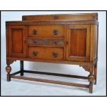 A 1930's  oak sideboard having a central bank of 2 drawers being flanked by cupbords. All raised