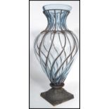 A large 20th century tall studio glass and worked metal vase the cast metal base rising and
