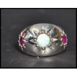 A sterling silver opal and ruby dress ring. The three stone ring being star set. Size S weighs 9