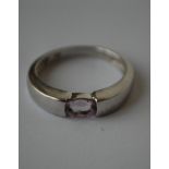 A hallmarked 9ct white gold ring set with a single oval cut pale purple stone.  Hallmarked