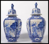 A pair of early 19th century Dutch Delft lidded vases / temple jars having bird finial lids.