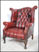 A 20th antique style Oxblood leather wing backed Chesterfield armchair with button back detailing to