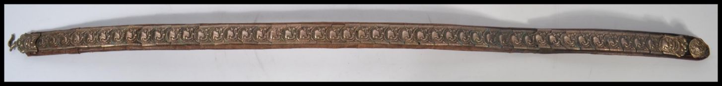 An unusual white metal and leather belt, believed early 20th century having unusual arabic design to