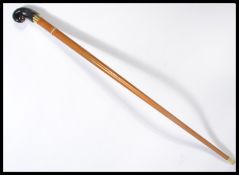 A vintage 20th century walking stick cane having a tapering wooden shaft with brass collar and