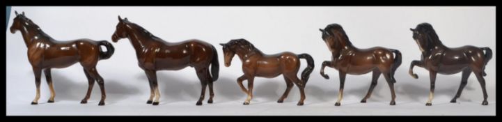 A group of five Beswick ceramic horse figurines in various stances. All in a gloss brown. One