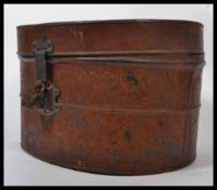 A 19th century Victorian tin hat box having a hinged lock and padlock to front with wood grain
