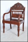 A carved hardwood chair - armchair being raised on turned legs united by peripheral stretchers,