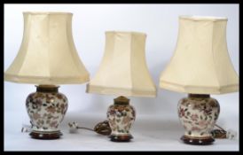 A set of three 20th century bulbous ceramic  table lamps in an Imari style pattern each retaining