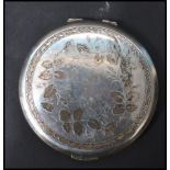 A silver hallmarked ladies compact, cast in relief with foliate design to the lid, machine turned