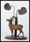 An early 20th century cold painted figurine of a stag raised on a plinth base with cast metal