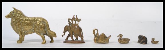 A cast brass figurine of a dog along with a graduating set of three swans , a Wise Monkeys brass