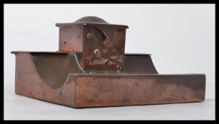 A 20th century Arts and Crafts hand beaten copper inkwell / desk tidy, central inkwell flanked by