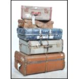A stack of 5 vintage 20th century suitcases to include a canvas bound wooden steamer trunk, mid