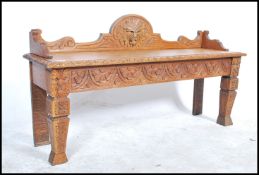 A Victorian 19th century profusely carved oak hall settle / window seat with green man mask to the
