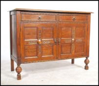 A 1930's oak Art Deco sideboard being raised on cup and cover supports with a sideboard