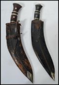 Two vintage 20th century Kukri knives in leather sheaf's one having smaller knives to the sheaf.