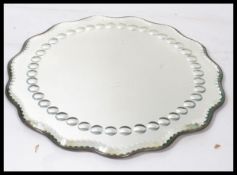 An early 20th century Art Deco bevelled glass mirror of scalloped form having a halo of smaller