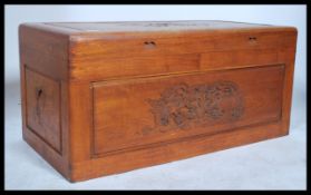 A mid 20th century Chinese camphorwood blanket box chest with carved scenes in relief having plain