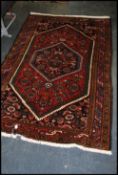 A 20th century Heriz Persian rug with central twin lozenge fielded centre on red ground with
