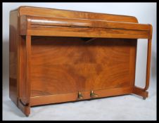 A post war Art Deco burr walnut Kemble Minx mini piano being iron framed in walnut case, the