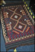 A 20th century handwoven kilim rug having chevron and medallion design with wave borders and tassled