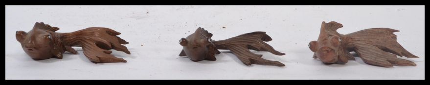 A group of three 20th century wooden caved Netsuke style carvings of Carp fish, each in a
