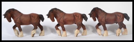 A matching set of three Beswick ceramic figures of shire horses in matt brown. Measures 21cms