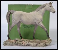 A large Beswick figurine of a horse in a white and grey dappled colourway raised on a naturalistic