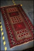 An Oriental Qashqai style wollen rug having red ground with central design of 5 panels,  geometric