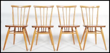 A set of 4 mid century retro Ercol dining chairs being raised on turned legs with stretchers, saddle