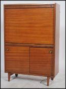 A mid century Danish influence teak wood cocktail cabinet of upright form having a fall front drinks