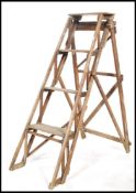 An early 20th century wooden Industrial step ladder with trellis worked sides having a-frame folding