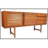 A 1970's McIntosh of Kirkaldy teak wood sideboard being raised on shaped legs with louvre doors