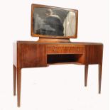 A 1970's teak wood space age dressing table being raised on tapering squared legs with a series of