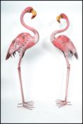 A pair of decorative cast metal pink flamingo's. Each of painted form raised on tall legs with