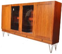 A large 1960's Danish inspired teak wood upright bookcase sideboard being raised on hairpin legs