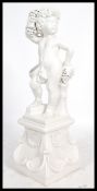 A large floor standing ceramic statue of a cherub / putti holding a bunch of grapes. Set over a
