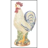 An early 20th century ceramic figurine of a cockerel having brightly coloured glazed finish,