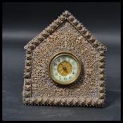 A 19th century gilt brass house shaped easel clock having a central barrel clock with an enamel face