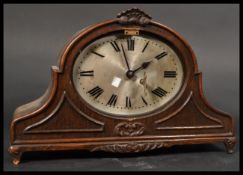 An Edwardian oak arched cased 8 day mantel clock having oval silvered dial with roman numeral