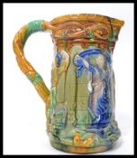 A believed Victorian 19th century majolica tower jug being relief moulded with medieval dancers in