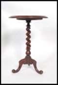A Victorian mahogany barleytwist wine table being raised on splayed legs with barley twist column