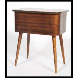 A vintage retro 20th century teak sewing box raised on tapering legs with hinged lid opening to