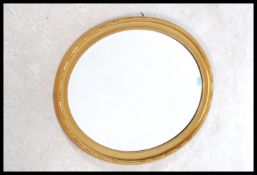 A 1930's gilt wood oval wall mirror. The shaped gilded oval frame with inset bevelled edge mirror