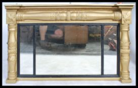 An antique style large ornate over mantle mirror having a gilt plaster and wood frame with columns