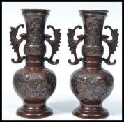 A pair of early 20th century Chinese bronze baluster vases raised on circular bases with scrolled