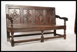 An early 18th century country oak settle bench. The back with recessed fielded panels over a bench