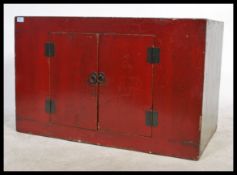 An early 20th Century Chinese plain  red lacquered chest / cabinet with two fitted doors on